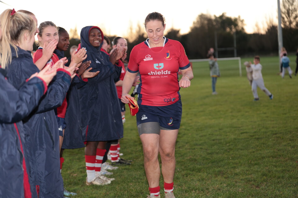 Chloe walks off pitch as teammates clap.