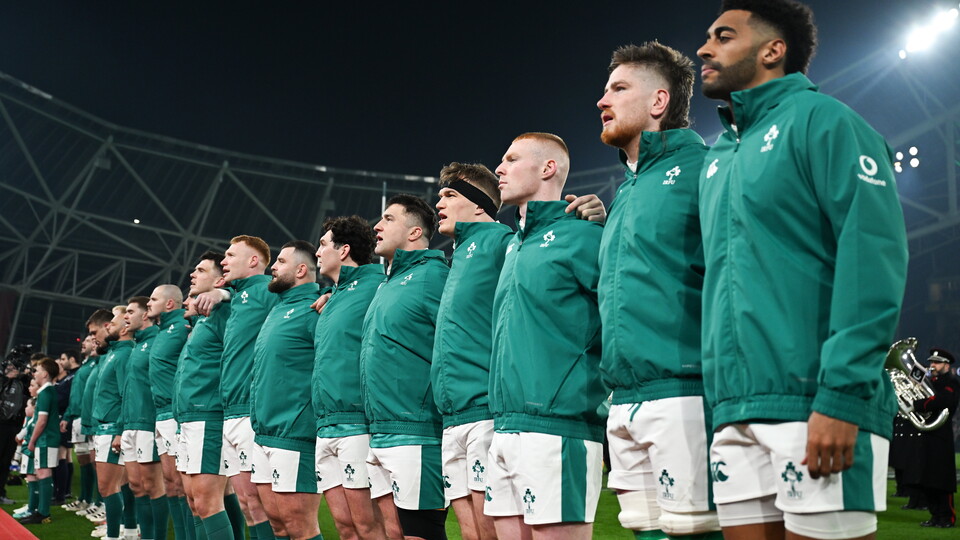 The Irish rugby team stands in a line, wearing green shirts and white shorts, during a match.