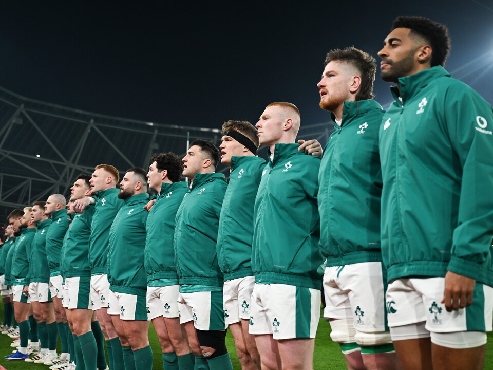 The Irish rugby team stands in a line, wearing green shirts and white shorts, during a match.